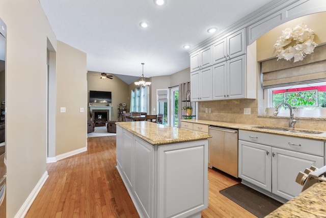 13191 Brandon Cir, Pickerington, OH 43147 - kitchen with dishwasher, a chandelier, a fireplace, a kitchen island, and light wood-style flooring