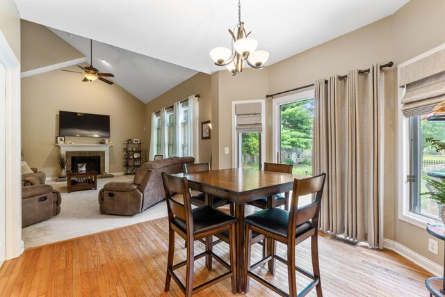 13191 Brandon Cir, Pickerington, OH 43147 - dining area with light wood-style flooring, a brick fireplace, a chandelier, a ceiling fan, and lofted ceiling