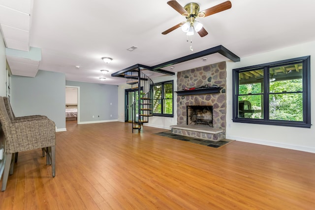 1800 Lynnbrook Ct, Orient, OH 43146 - unfurnished living room featuring stairway, a ceiling fan, wood finished floors, and a stone fireplace