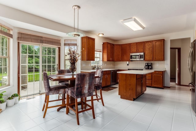 5630 Dorshire Dr, Galena, OH 43021 - kitchen with appliances with stainless steel finishes, light countertops, a center island, brown cabinets, and decorative backsplash