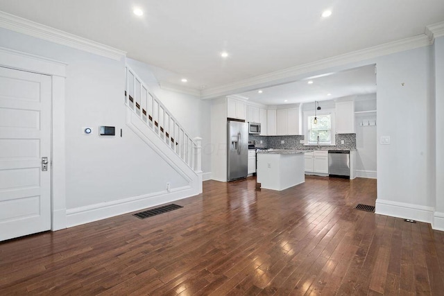 1382 S 5th St, Columbus, OH 43207 - kitchen with stainless steel appliances, dark wood-style flooring, decorative backsplash, a kitchen island, and white cabinetry