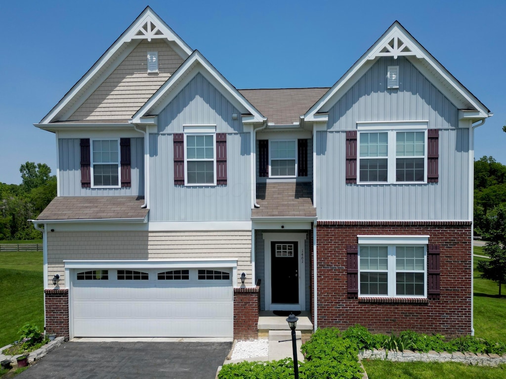 1461 Hoovler Way, Pataskala, OH 43062 - view of front facade featuring board and batten siding, asphalt driveway, brick siding, and an attached garage
