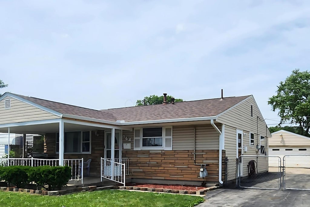 164 E Alcott Rd, Columbus, OH 43207 - view of front of home featuring covered porch, an outbuilding, a garage, and a shingled roof