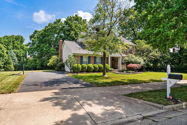 7672 Tullymore Dr, Dublin, OH 43016 - view of front facade with a front lawn, brick siding, driveway, and a chimney