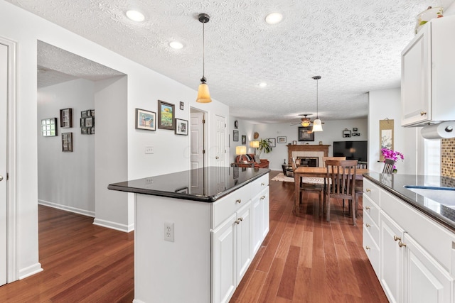 7672 Tullymore Dr, Dublin, OH 43016 - kitchen with dark countertops, dark wood-style floors, white cabinetry, open floor plan, and a textured ceiling