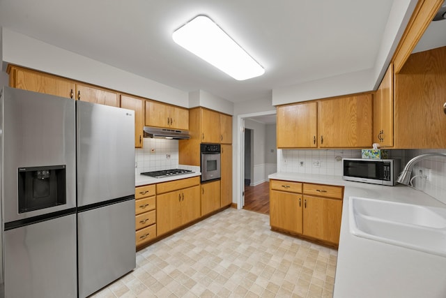 2681 Montcalm Rd, Columbus, OH 43221 - kitchen featuring appliances with stainless steel finishes, under cabinet range hood, light countertops, tasteful backsplash, and light floors