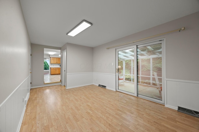 2681 Montcalm Rd, Columbus, OH 43221 - empty room featuring light wood-type flooring, a wainscoted wall, and a decorative wall