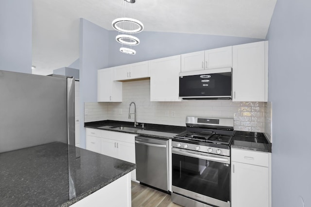 3751 Dolomite Dr, Columbus, OH 43230 - kitchen with appliances with stainless steel finishes, vaulted ceiling, white cabinetry, decorative backsplash, and dark stone counters