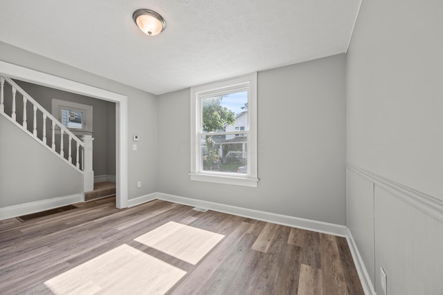1765 S 8th St, Columbus, OH 43207 - spare room with stairway, wood finished floors, a wainscoted wall, and a textured ceiling