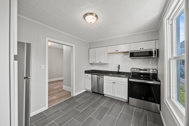 1765 S 8th St, Columbus, OH 43207 - kitchen featuring appliances with stainless steel finishes, crown molding, backsplash, white cabinets, and a textured ceiling