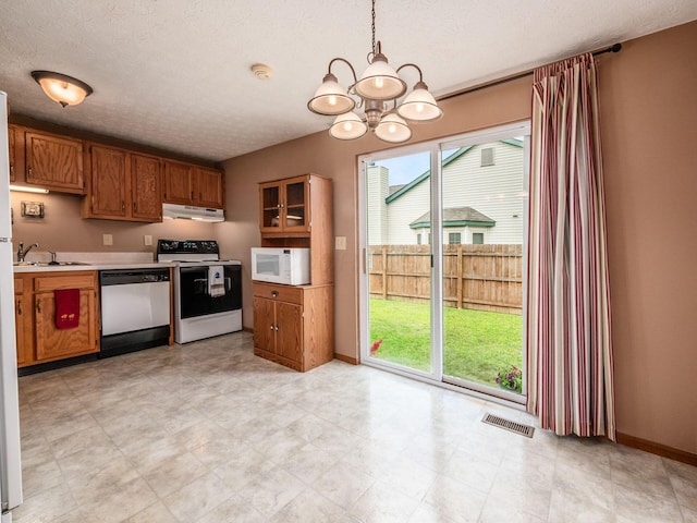 1225 El Toro Dr, Columbus, OH 43204 - kitchen with white appliances, under cabinet range hood, a chandelier, light countertops, and brown cabinets