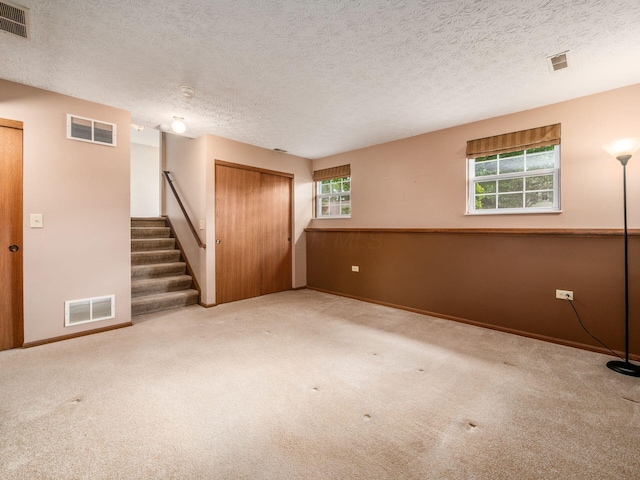 1225 El Toro Dr, Columbus, OH 43204 - unfurnished room with healthy amount of natural light, carpet flooring, stairs, and a textured ceiling