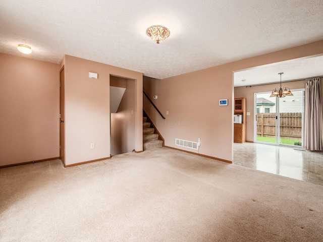 1225 El Toro Dr, Columbus, OH 43204 - unfurnished living room featuring carpet flooring, stairs, a chandelier, and a textured ceiling