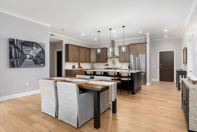 225 John H Mcconnell Blvd Unit 605, Columbus, OH 43215 - kitchen featuring wall chimney range hood, stainless steel appliances, a center island with sink, decorative backsplash, and light wood-style floors