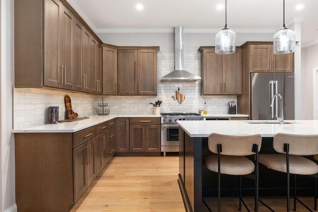 225 John H Mcconnell Blvd Unit 605, Columbus, OH 43215 - kitchen featuring wall chimney range hood, high end appliances, a breakfast bar area, ornamental molding, and light wood-style floors