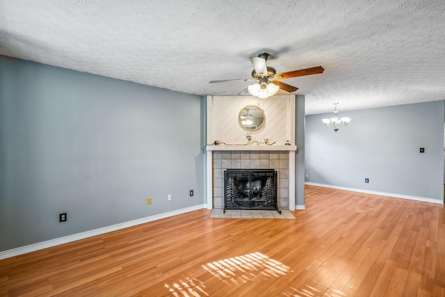 4905 Mckenna Ct, Columbus, OH 43221 - unfurnished living room featuring wood finished floors, ceiling fan, a tiled fireplace, a chandelier, and a textured ceiling