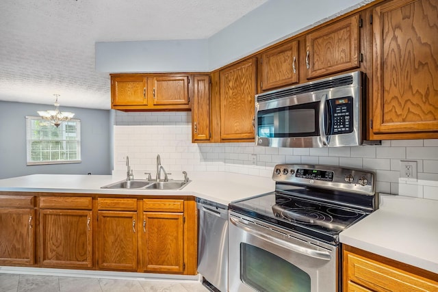 4905 Mckenna Ct, Columbus, OH 43221 - kitchen with appliances with stainless steel finishes, a textured ceiling, light countertops, a chandelier, and brown cabinetry