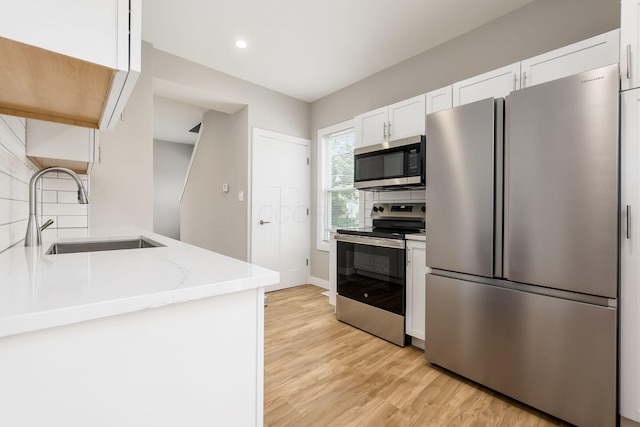 310 S Ogden Ave, Columbus, OH 43204 - kitchen featuring appliances with stainless steel finishes, white cabinets, decorative backsplash, light wood-style flooring, and recessed lighting