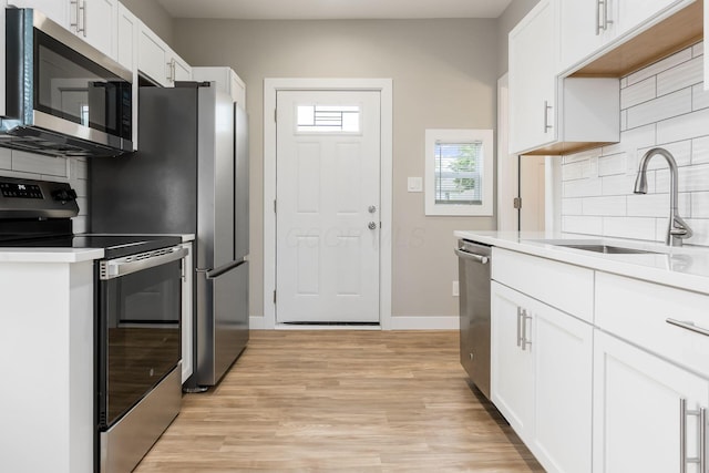 310 S Ogden Ave, Columbus, OH 43204 - kitchen featuring stainless steel appliances, backsplash, white cabinets, and light wood-style floors