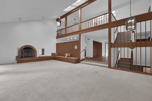 71 Denison Dr, Granville, OH 43023 - unfurnished living room featuring a brick fireplace, stairs, high vaulted ceiling, carpet flooring, and a chandelier