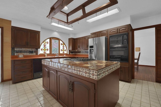 71 Denison Dr, Granville, OH 43023 - kitchen with black appliances, a kitchen island, backsplash, and light tile patterned floors