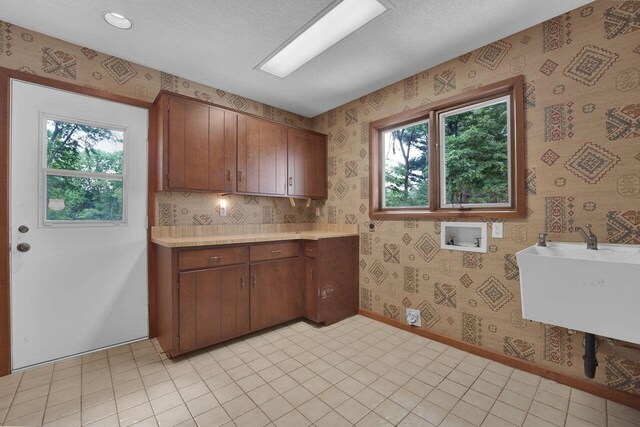 71 Denison Dr, Granville, OH 43023 - kitchen with wallpapered walls, plenty of natural light, light countertops, and brown cabinetry