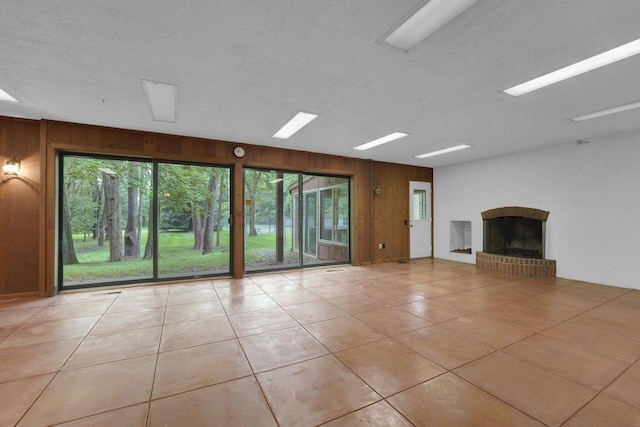 71 Denison Dr, Granville, OH 43023 - unfurnished living room featuring wooden walls, a brick fireplace, tile patterned flooring, and a textured ceiling