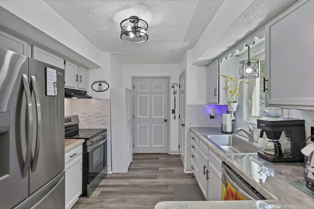 389 Fenway Rd Unit B, Columbus, OH 43214 - kitchen featuring stainless steel appliances, under cabinet range hood, wood finished floors, a textured ceiling, and light countertops