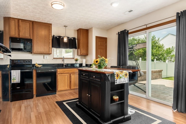 281 Inah Ave, Columbus, OH 43228 - kitchen featuring black appliances, light wood-style floors, plenty of natural light, brown cabinets, and a textured ceiling