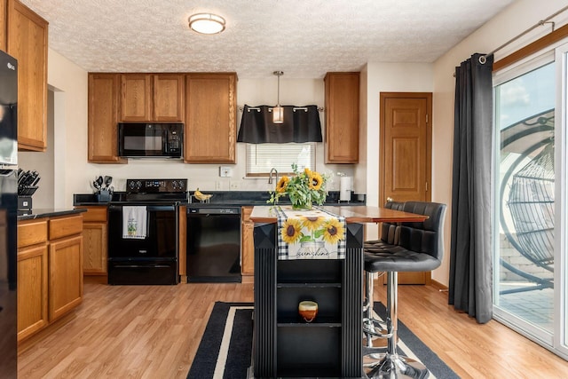 281 Inah Ave, Columbus, OH 43228 - kitchen with black appliances, light wood-style flooring, dark countertops, brown cabinetry, and a textured ceiling