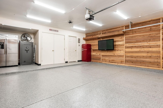 281 Inah Ave, Columbus, OH 43228 - garage featuring stainless steel refrigerator with ice dispenser, wood walls, and a garage door opener