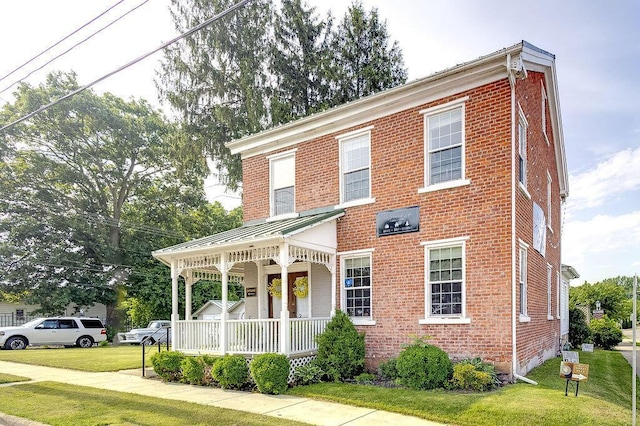 100 E Ohio Ave, Mount Vernon, OH 43050 - view of front of property featuring covered porch, brick siding, a front lawn, a standing seam roof, and a metal roof