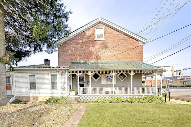 100 E Ohio Ave, Mount Vernon, OH 43050 - view of front facade with a porch, brick siding, a front lawn, a standing seam roof, and a chimney
