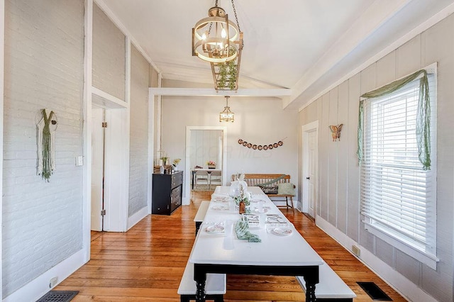100 E Ohio Ave, Mount Vernon, OH 43050 - dining area with a chandelier, lofted ceiling, light wood finished floors, and brick wall