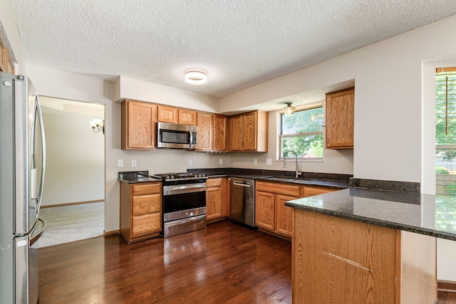 7345 Oakmeadows Dr, Columbus, OH 43085 - kitchen with stainless steel appliances, a peninsula, dark wood-type flooring, a textured ceiling, and brown cabinetry