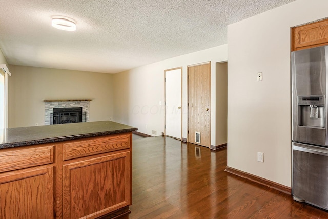 7345 Oakmeadows Dr, Columbus, OH 43085 - kitchen featuring stainless steel fridge with ice dispenser, dark wood-style floors, a textured ceiling, a fireplace, and brown cabinetry