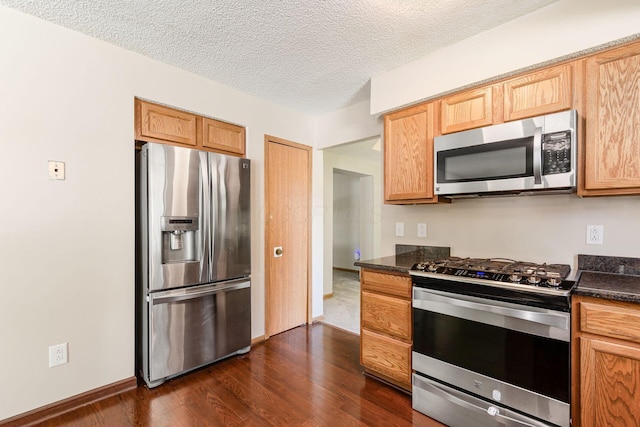 7345 Oakmeadows Dr, Columbus, OH 43085 - kitchen with stainless steel appliances, dark countertops, dark wood-style flooring, and a textured ceiling