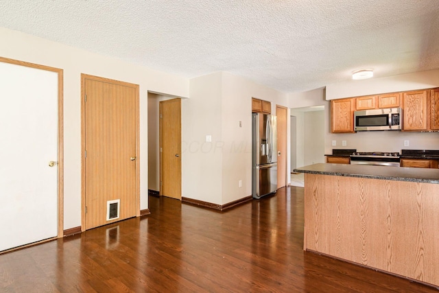 7345 Oakmeadows Dr, Columbus, OH 43085 - kitchen with appliances with stainless steel finishes, dark countertops, dark wood-type flooring, and a textured ceiling