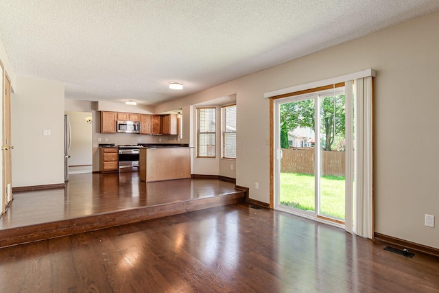 7345 Oakmeadows Dr, Columbus, OH 43085 - kitchen featuring stainless steel appliances, dark countertops, dark wood finished floors, a textured ceiling, and brown cabinetry