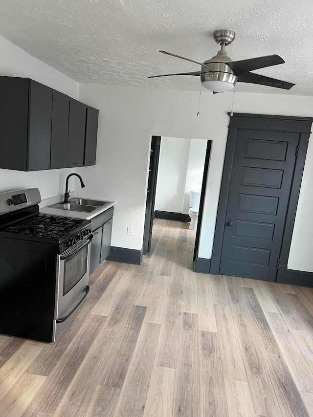 51 E N St, Newark, OH 43055 - kitchen with gas range, a textured ceiling, ceiling fan, dark cabinets, and light wood finished floors