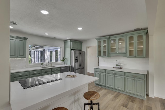 1080 Coonpath Rd NW, Lancaster, OH 43130 - kitchen with green cabinets, stainless steel appliances, a textured ceiling, a breakfast bar area, and decorative backsplash
