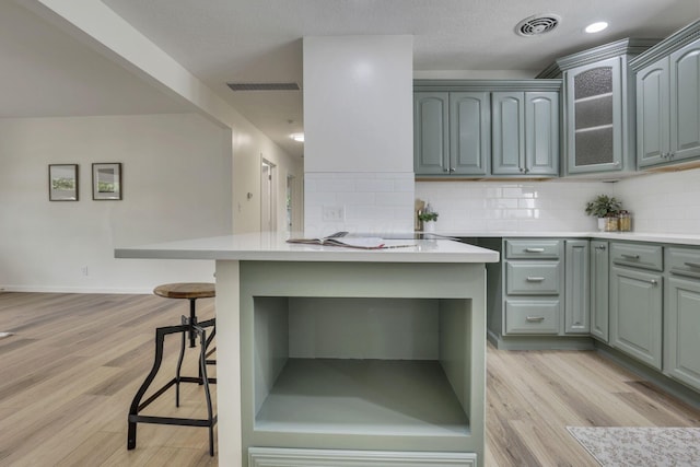 1080 Coonpath Rd NW, Lancaster, OH 43130 - kitchen featuring a breakfast bar area, light countertops, tasteful backsplash, and glass insert cabinets