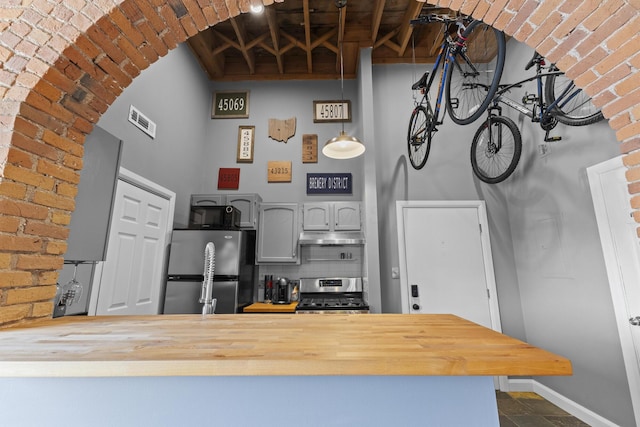 51 W Blenkner St Unit 306, Columbus, OH 43215 - kitchen featuring appliances with stainless steel finishes, butcher block countertops, under cabinet range hood, a high ceiling, and a peninsula