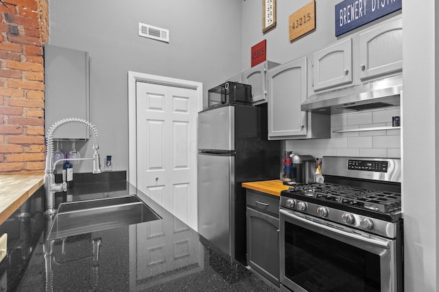 51 W Blenkner St Unit 306, Columbus, OH 43215 - kitchen featuring appliances with stainless steel finishes, under cabinet range hood, tasteful backsplash, wood counters, and a towering ceiling