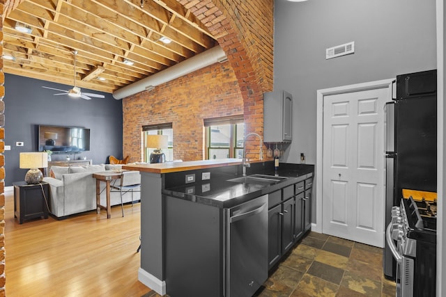 51 W Blenkner St Unit 306, Columbus, OH 43215 - kitchen with stainless steel appliances, a towering ceiling, ceiling fan, a peninsula, and brick wall