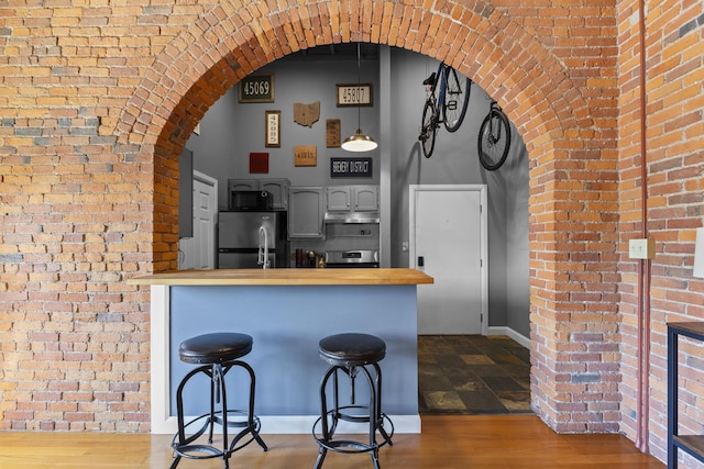51 W Blenkner St Unit 306, Columbus, OH 43215 - kitchen with freestanding refrigerator, wooden counters, arched walkways, brick wall, and a kitchen bar