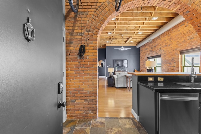 51 W Blenkner St Unit 306, Columbus, OH 43215 - kitchen featuring stainless steel dishwasher, ceiling fan, brick wall, stone finish floors, and arched walkways
