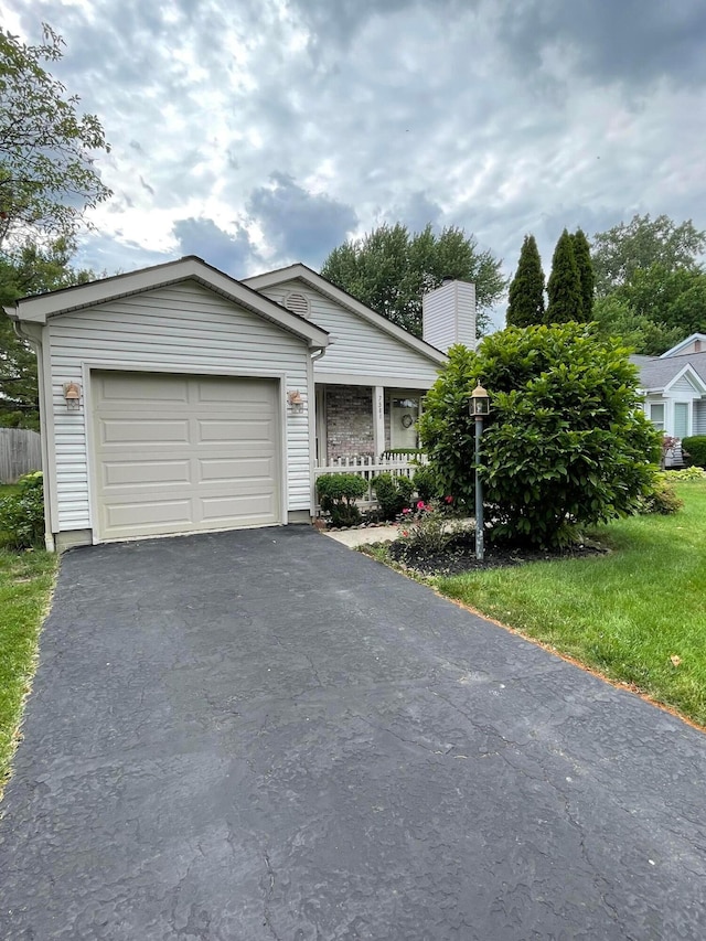 7581 Toweron Ln, Columbus, OH 43235 - view of front facade with asphalt driveway, an attached garage, a porch, a chimney, and a front lawn