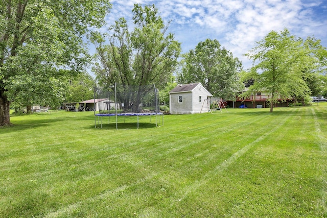748 Forward Pass Rd SW, Pataskala, OH 43062 - view of green lawn featuring a trampoline, a wooden deck, an outbuilding, and view of scattered trees