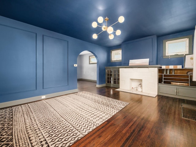 211 E Jenkins Ave, Columbus, OH 43207 - unfurnished living room featuring arched walkways, wood finished floors, and a chandelier